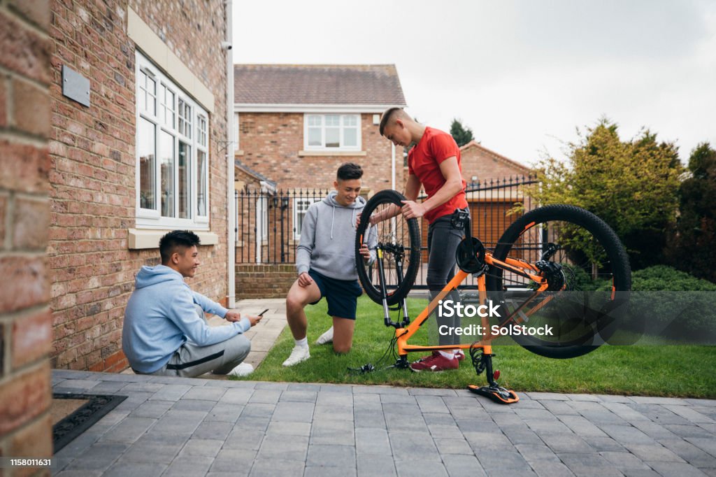 Tre ragazzi che riparano una mountain bike in giardino.