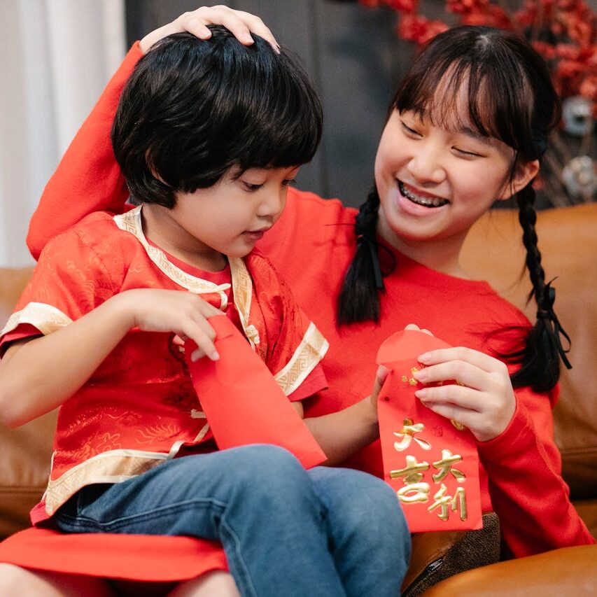 Due bambini cinesi vestiti di rosso si scambiano gli hongbao