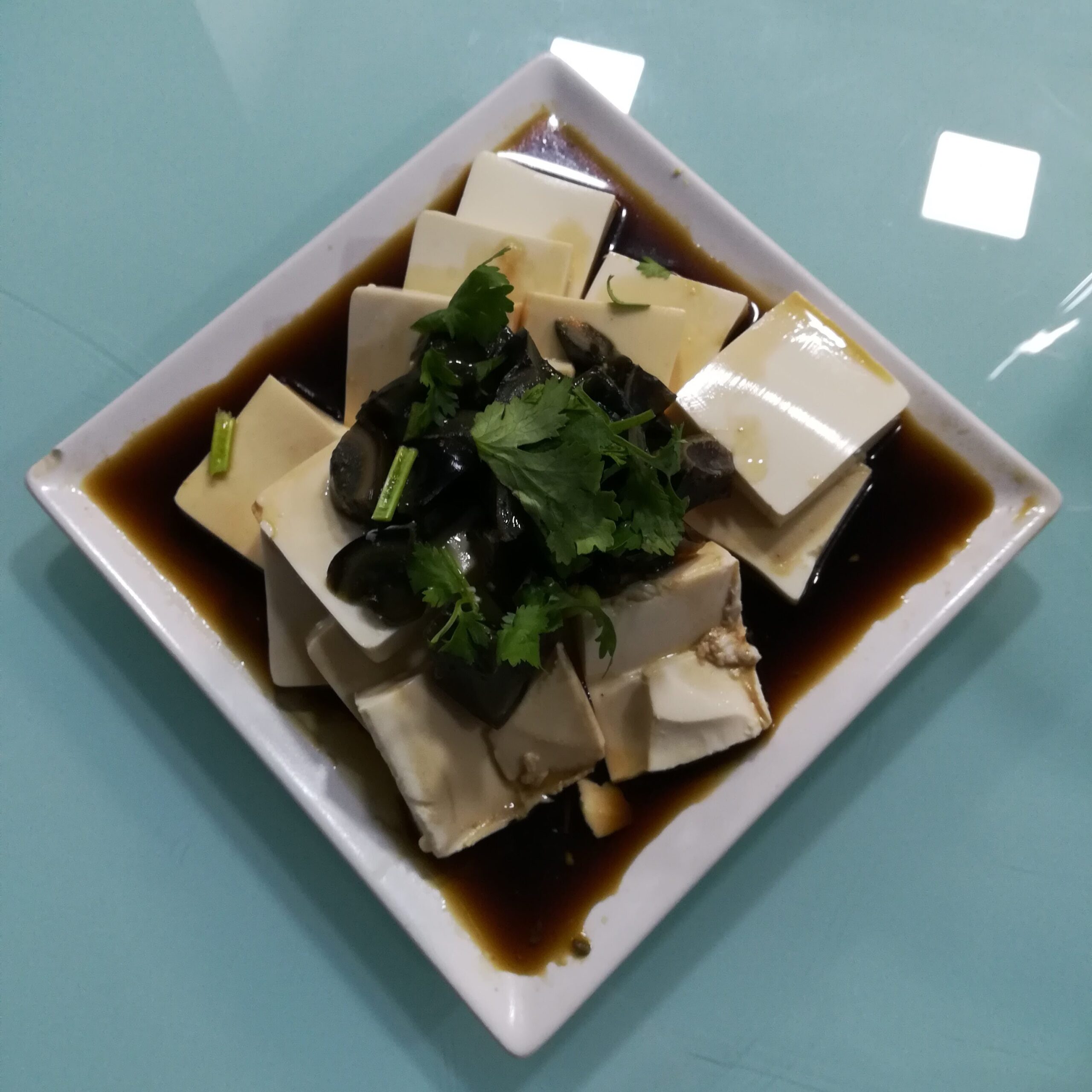 Piatto tipico della Cina: uovo centenario, tofu, coriandolo e salsa di soia