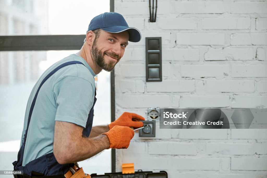 Elettricista che ripara una presa.